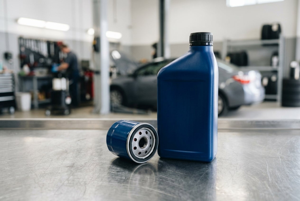 A blue motor oil bottle and oil filter sit on a metal workbench inside a car repair shop. (Representative image for illustration purposes only. Actual vehicle may vary based on trim and configuration.)