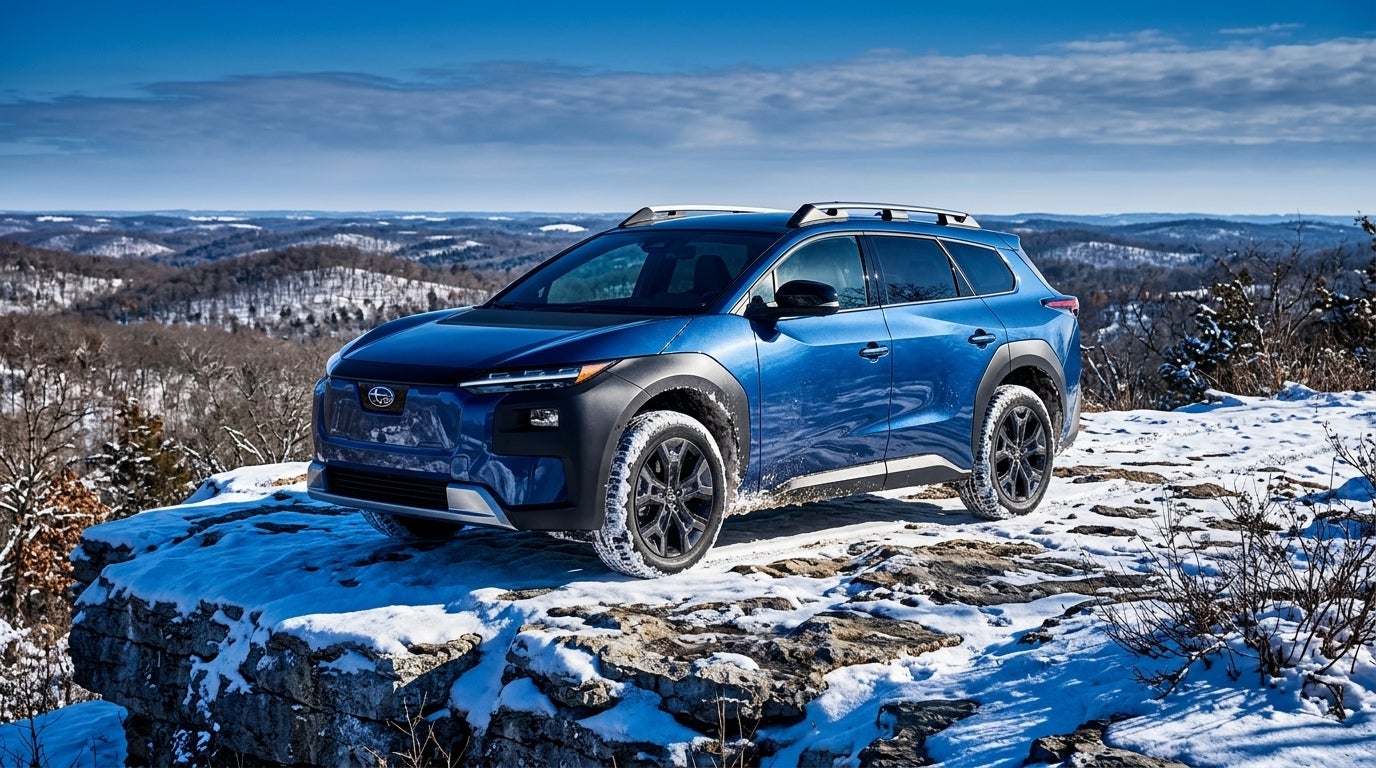 AI generated: Commercial photography, eye level, a rugged 2026 Subaru Trailseeker electric SUV parked on a snowy limestone overlook in the Missouri Ozarks near Sunset Hills, the vehicle's metallic exterior reflecting the dramatic high-contrast winter sunlight, dusting of fresh white snow on the rolling hills and dormant oak trees in the background, vibrant and saturated color palette with deep blues in the shadows and bright white highlights, Missouri winter atmosphere, heavy snowfall clinging to the vehicle's fenders and the rocky terrain, wide-angle lens capturing the expansive horizon of the Mark Twain National Forest, majestic and adventurous mood, crisp and sharp details, advertising style.