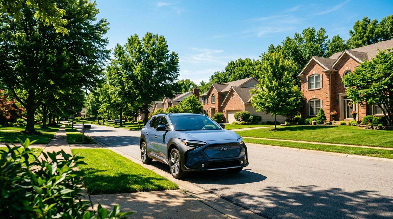 Photorealistic CGI, cinematic wide shot, a modern electric Subaru Solterra parked on a clean, sun-drenched suburban street in Sunset Hills, Missouri, early summer afternoon, June 24, 2026, clear blue sky, dramatic high contrast lighting with long shadows, vibrant and saturated color palette, lush green Missouri deciduous trees and manicured lawns, typical mid-western two-story brick and siding family homes in the background, heat shimmer on the asphalt, sharp reflections of the bright sun on the vehicle's metallic finish, low camera angle emphasizing the rugged stance and symmetrical all-wheel-drive heritage, no people, no text, clean and pristine atmosphere, peaceful neighborhood ambiance.