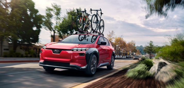 Unlimited A red Solterra Premium drives up a small town road with two bikes loaded on top.