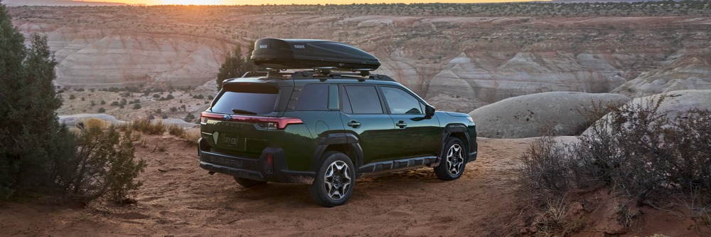 Rear 3/4 exterior static beauty major of the 2026 Outback Touring in Deep Emerald Pearl parked at a scenic canyon overlook. Thule roof cargo box accessory on roof racks. Rear 3/4 exterior static beauty major of the 2026 Outback Touring in Deep Emerald Pearl parked at a scenic canyon overlook. Thule roof cargo box accessory on roof racks.