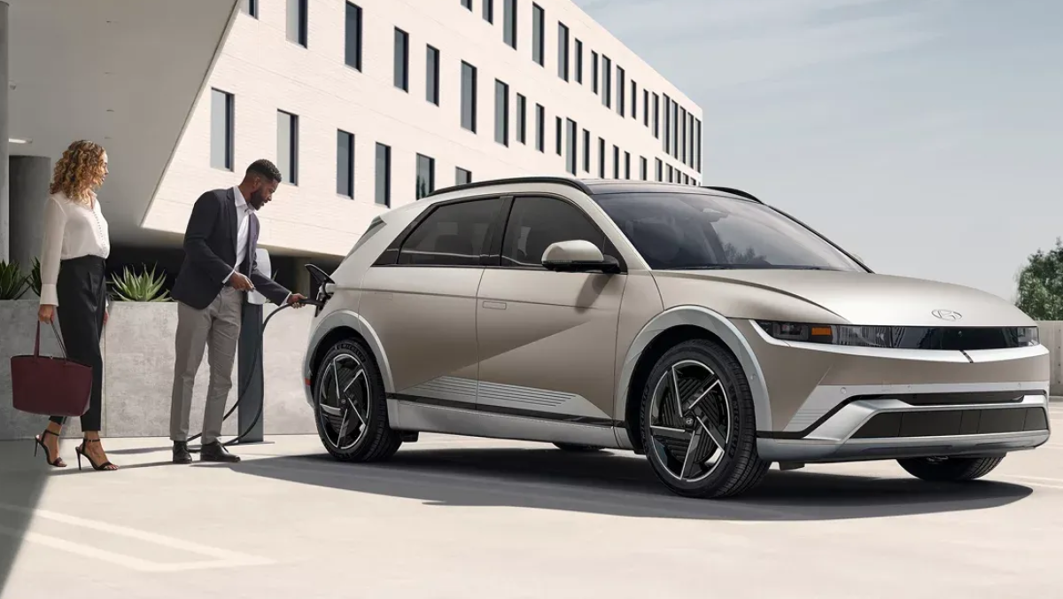2025 IONIQ 5 in Gravity Gold Matte with a person plugging it into a charger