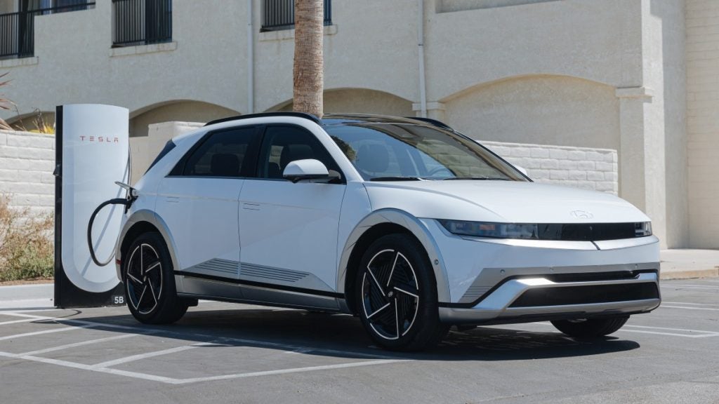 Front side view of a 2025 Hyundai IONIQ 5 Parked and plugged into a Tesla Charger