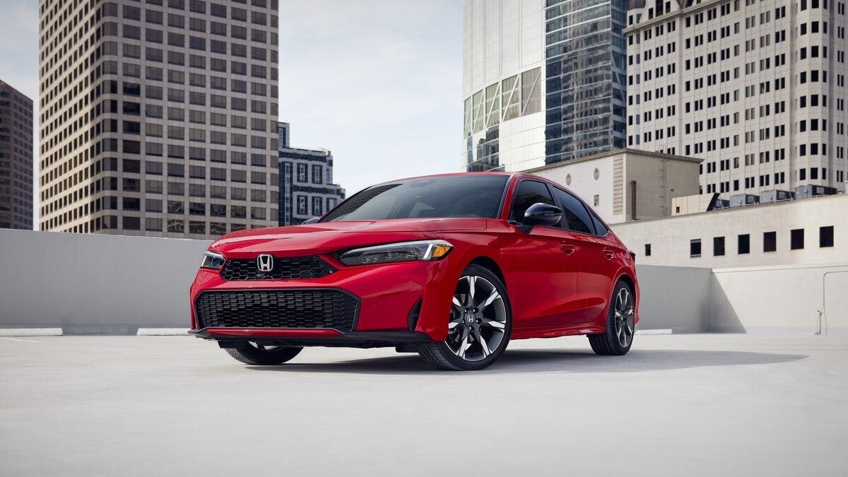 Red 2026 Honda Civic Sedan Sport Touring Hybrid parked in a city.