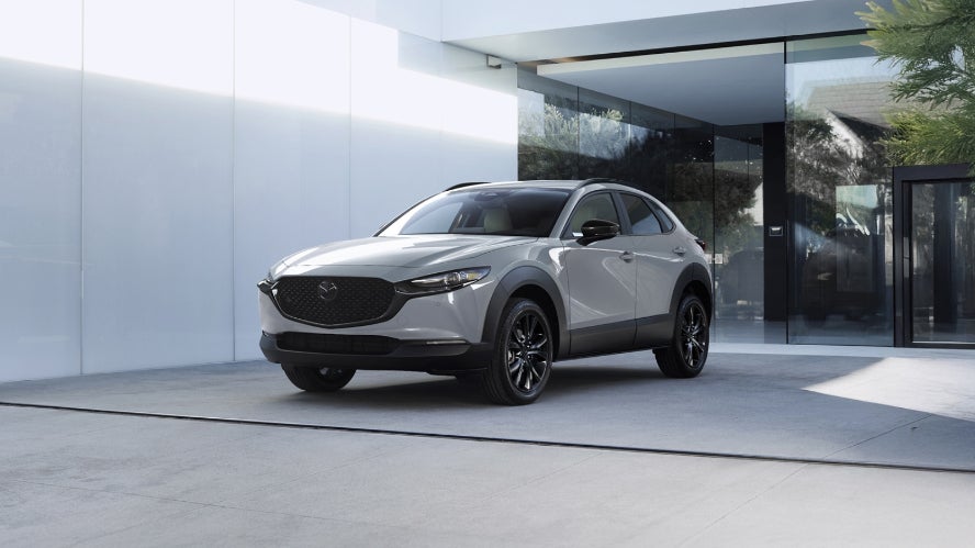 A white Mazda CX-30 parked in front of a building.