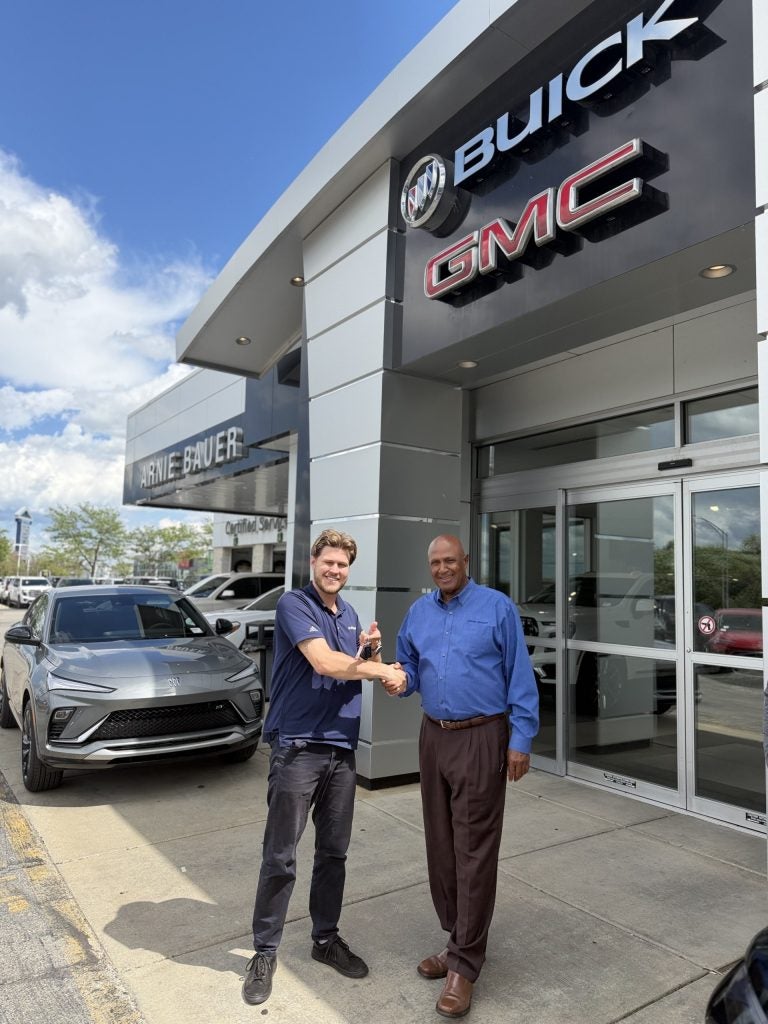 A happy customer is receiving keys to their new car after trading in a vehicle they still owed money on.