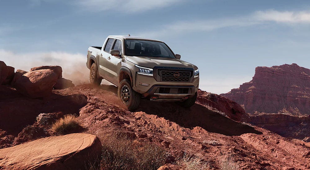 A grey 2024 Nissan Frontier PRO-4X driving down a rocky cliff.