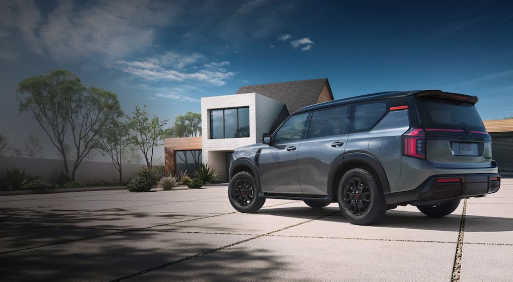 Rear view of a grey 2025 Nissan Armada XL parked outside a house after visiting a Nissan dealer near me.