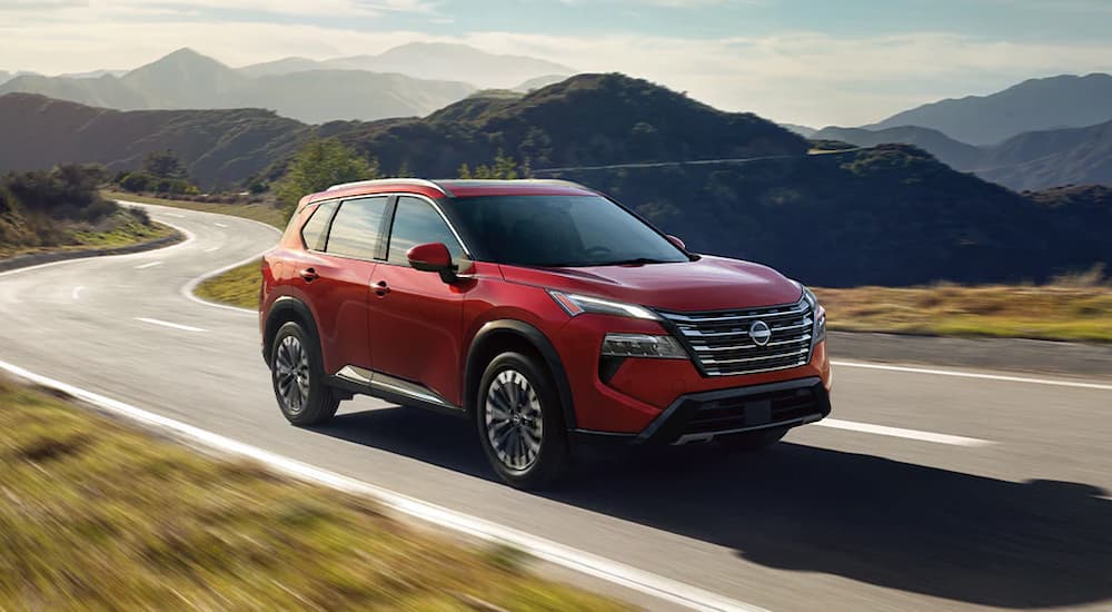 A red 2025 Nissan Rogue driving down a highway