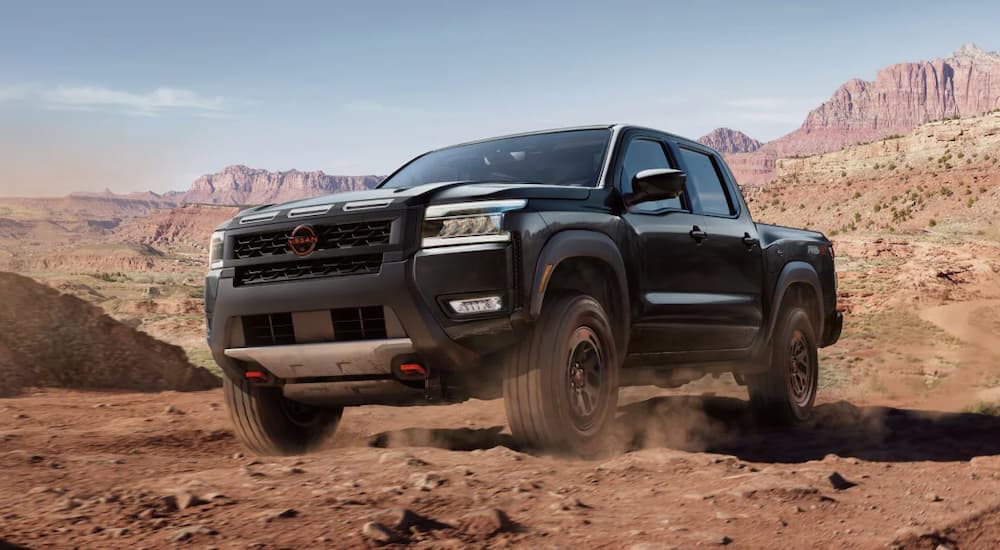 A black 2025 Nissan Frontier for sale in Knoxville driving off-road in a desert.