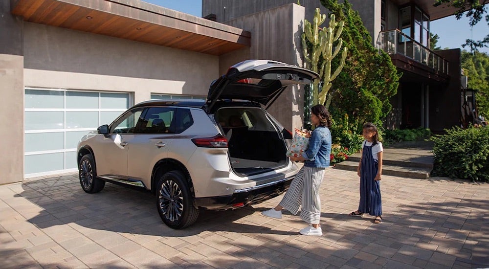 A person opening the trunk of a white 2024 Nissan Rogue.