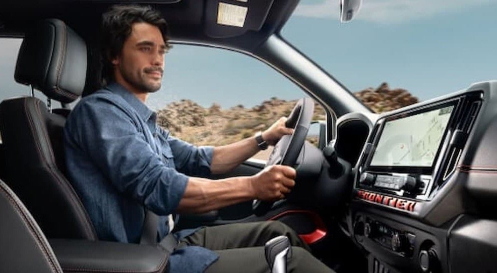 A person driving in a 2026 Nissan Frontier.