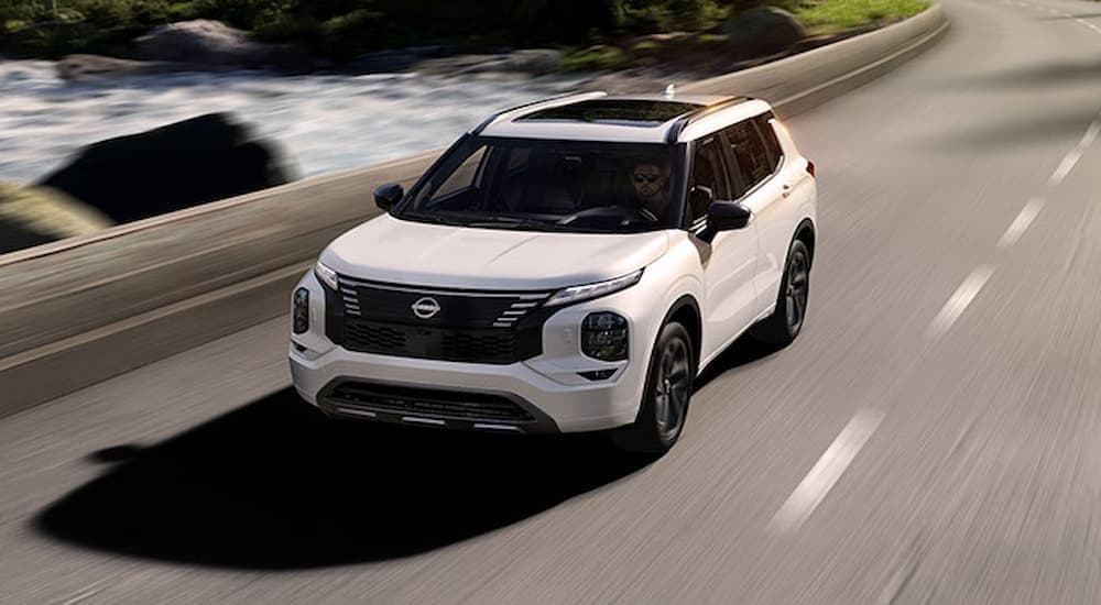 A white 2026 Nissan Rogue driving on a highway.