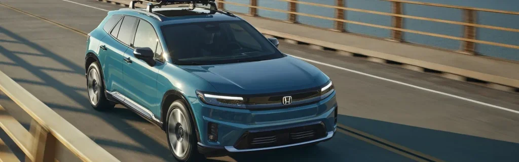 A blue Honda Prologue SUV driving on a bridge.
