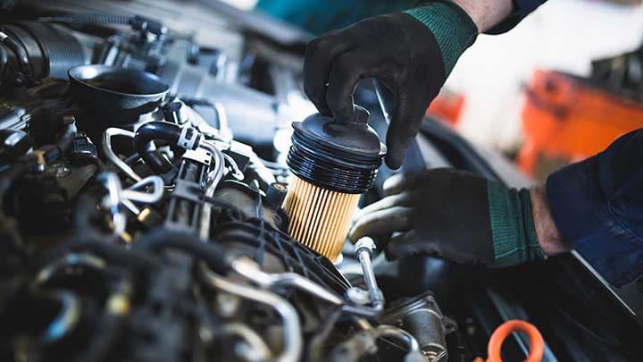 A mechanic replacing the oil filter in a car engine.