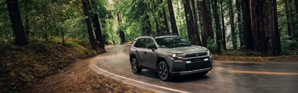A Toyota RAV4 driving along a winding road through a forest.