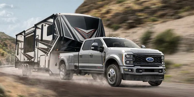 A 2023 Ford F-250 towing an RV while driving down the road near Lancaster, OH