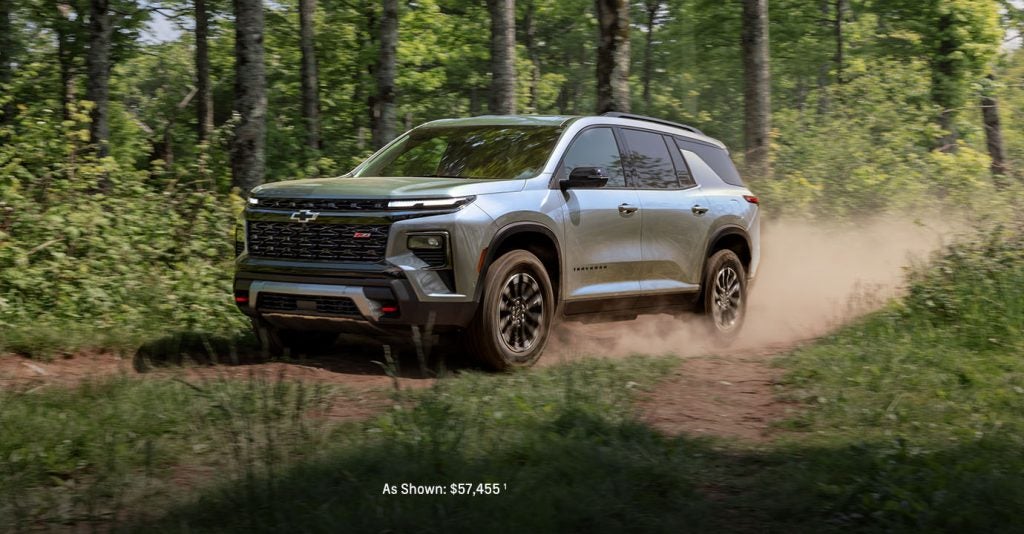 SUV driving on a forest trail, kicking up dust.