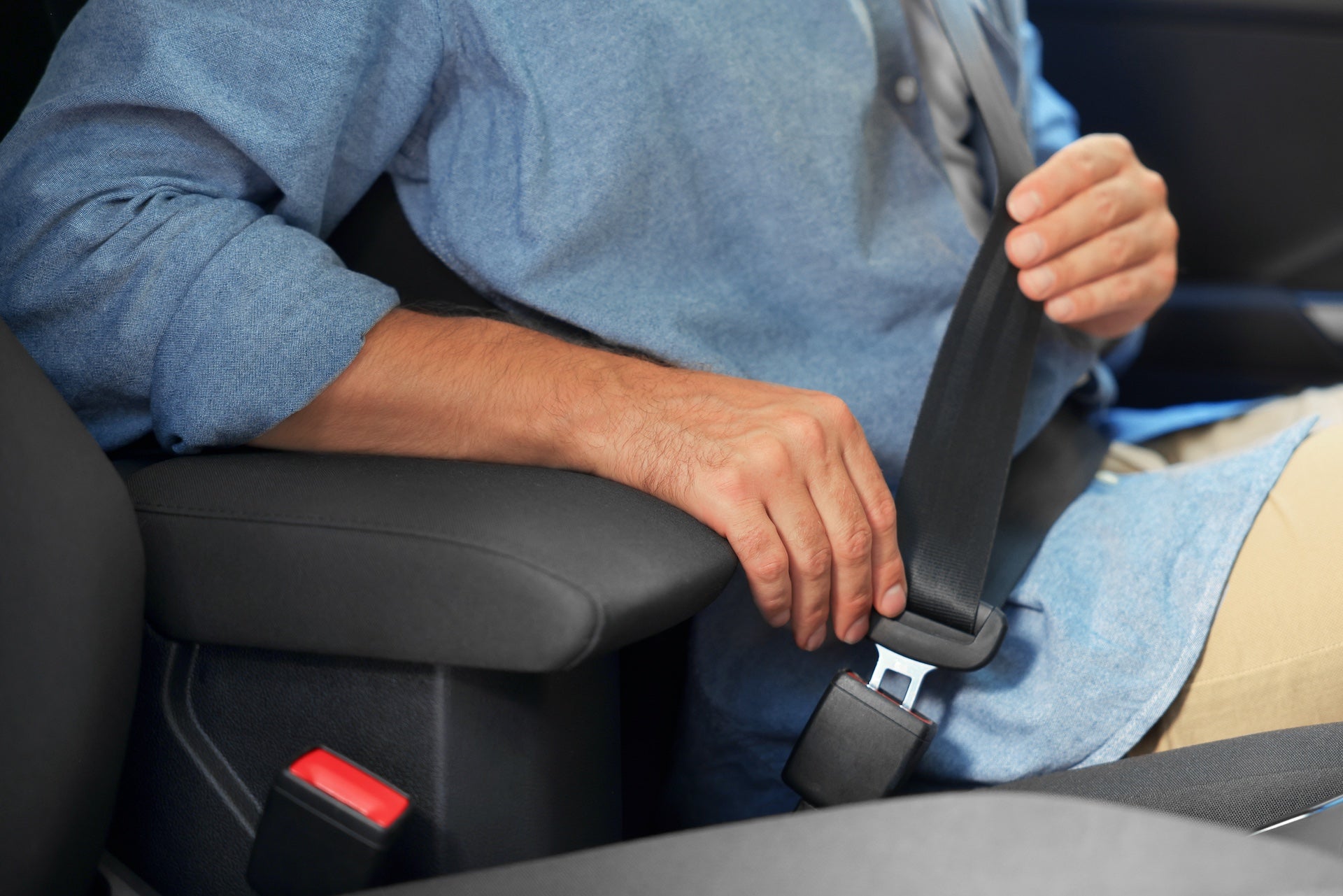 Man fastening safety seat belt in car, closeup