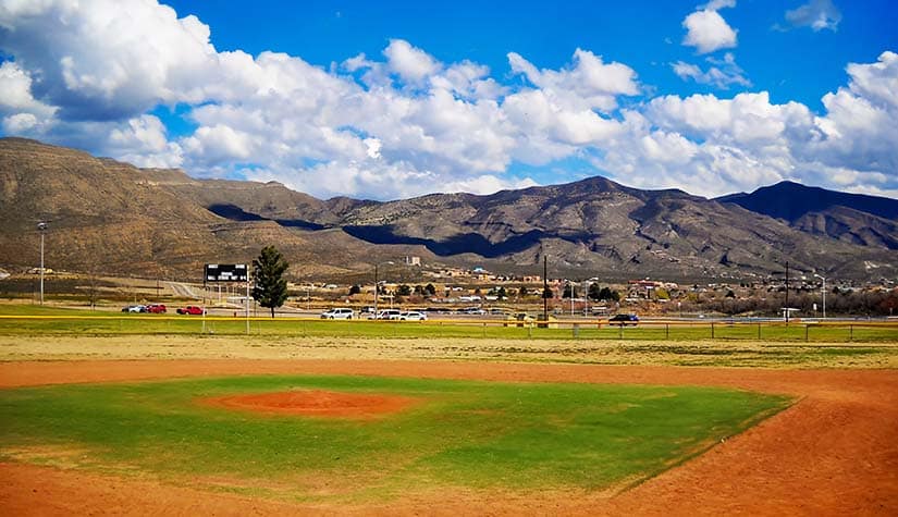 a baseball field surrounded by mountains on a beautiful sunny day 