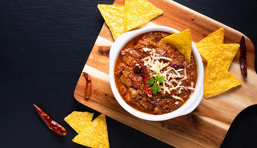 image of chili in a bowl and chips with assorted chilles on a cutting board