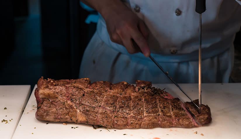 a chef cuts a large cut of meat