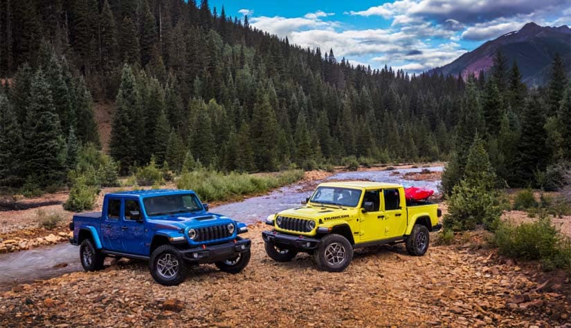 a blue and yellow jeep parked diagonally next to each other in a forest