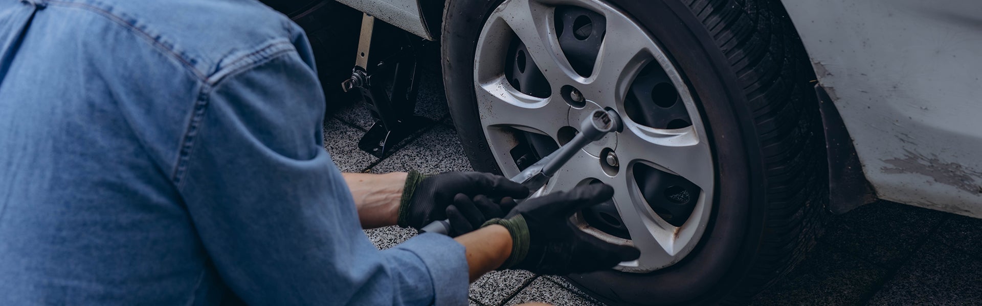 Person using a lug wrench to change a car tire.
