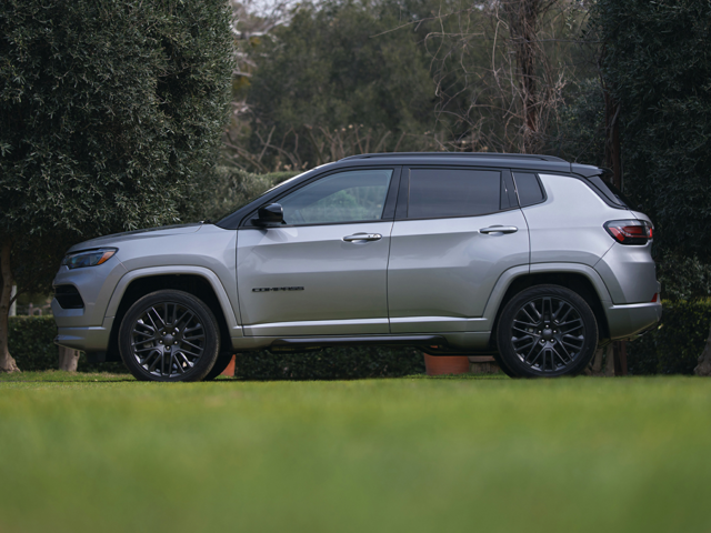 Profile view of a silver 2024 Jeep Compass parked on grass with trees in the background | Jeep dealer in Hampton, VA | Banister CDJR Hampton