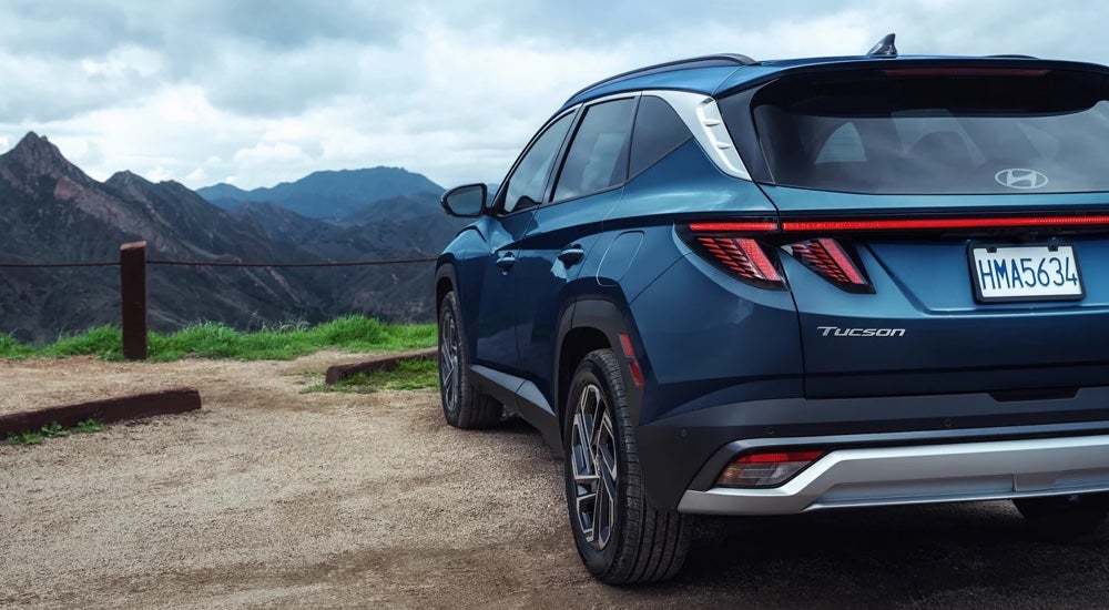 Rear view of a blue 2025 Hyundai Tucson Limited parked at a mountain overlook.