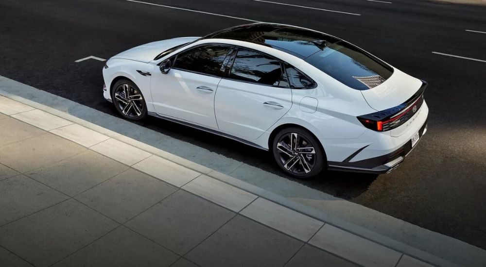 High angle rear view of a white 2024 Hyundai Sonata N-Line parked by a curb.