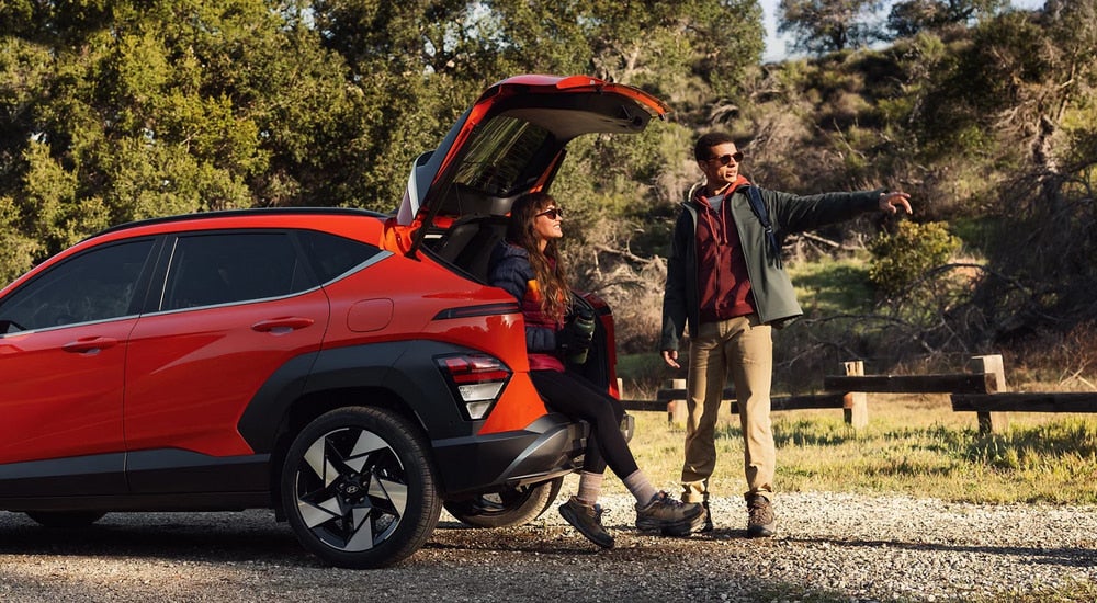 Two people getting ready for a hike next to an orange 2026 Hyundai Kona
