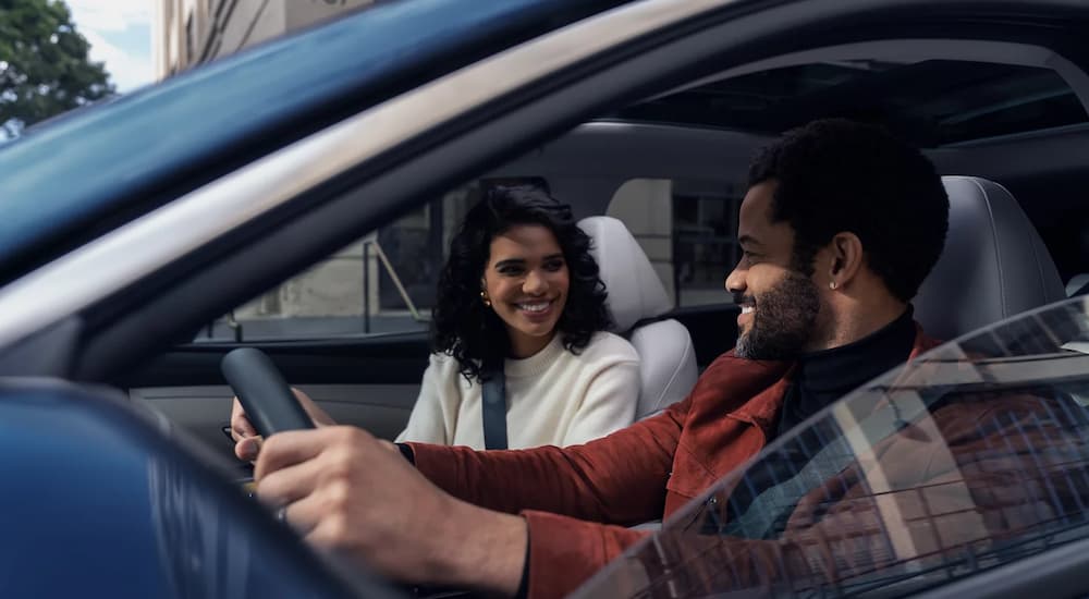 A couple driving a blue 2026 Hyundai Tucson in a city