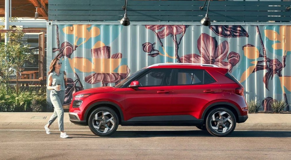 A red 2023 Hyundai Venue is shown from a side angle while parked by a used Hyundai dealer.