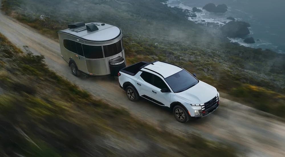 A white 2026 Hyundai Santa Cruz towing a trailer.