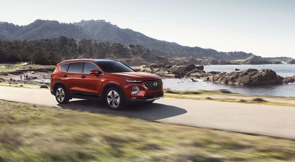 An orange 2019 Hyundai Santa Fe is shown driving.