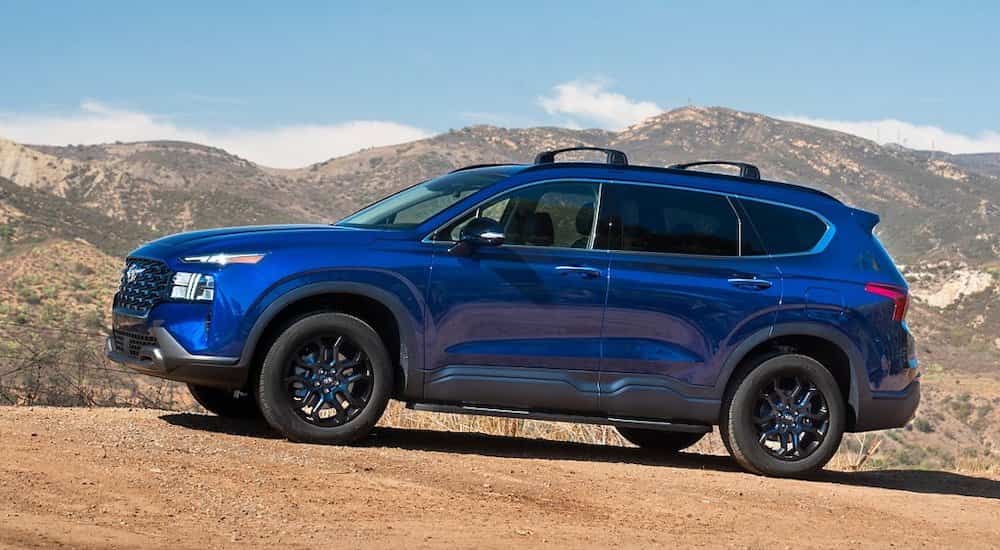A blue 2022 Hyundai Santa Fe is shown from the side after leaving a dealer that has used SUVs for sale.