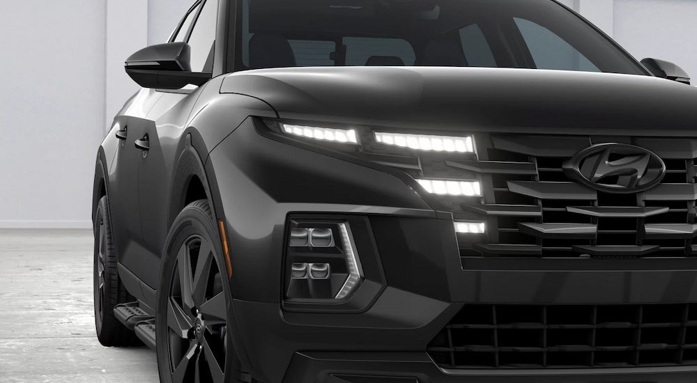 The grille and daytime running lights on a black 2024 Hyundai Santa Cruz Night.