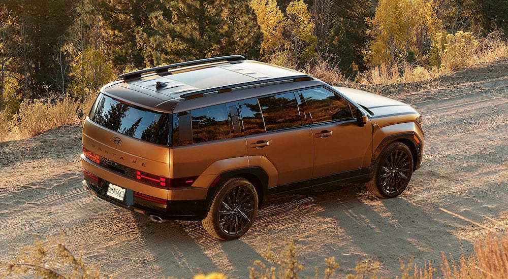 High rear angle view of a brown 2025 Hyundai Santa Fe driving off-road.