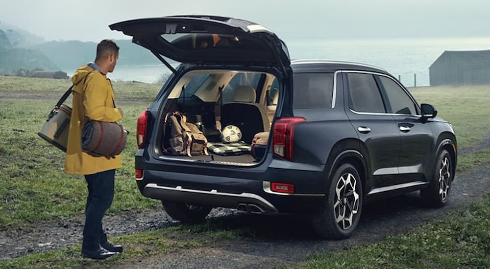 A person is shown looking at the open hatchback of a black 2021 Hyundai Palisade.