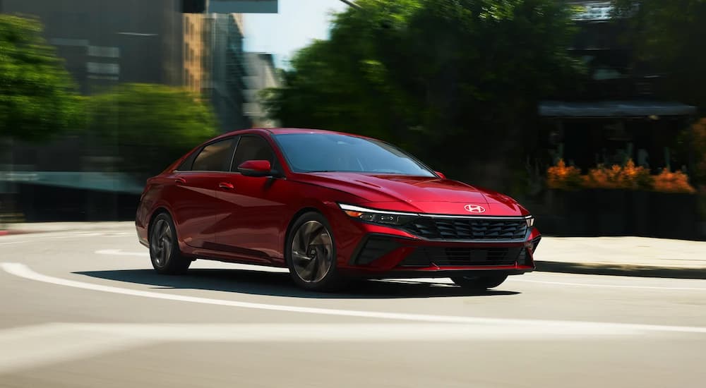 A red 2024 Hyundai Elantra Limited driving on a city street.