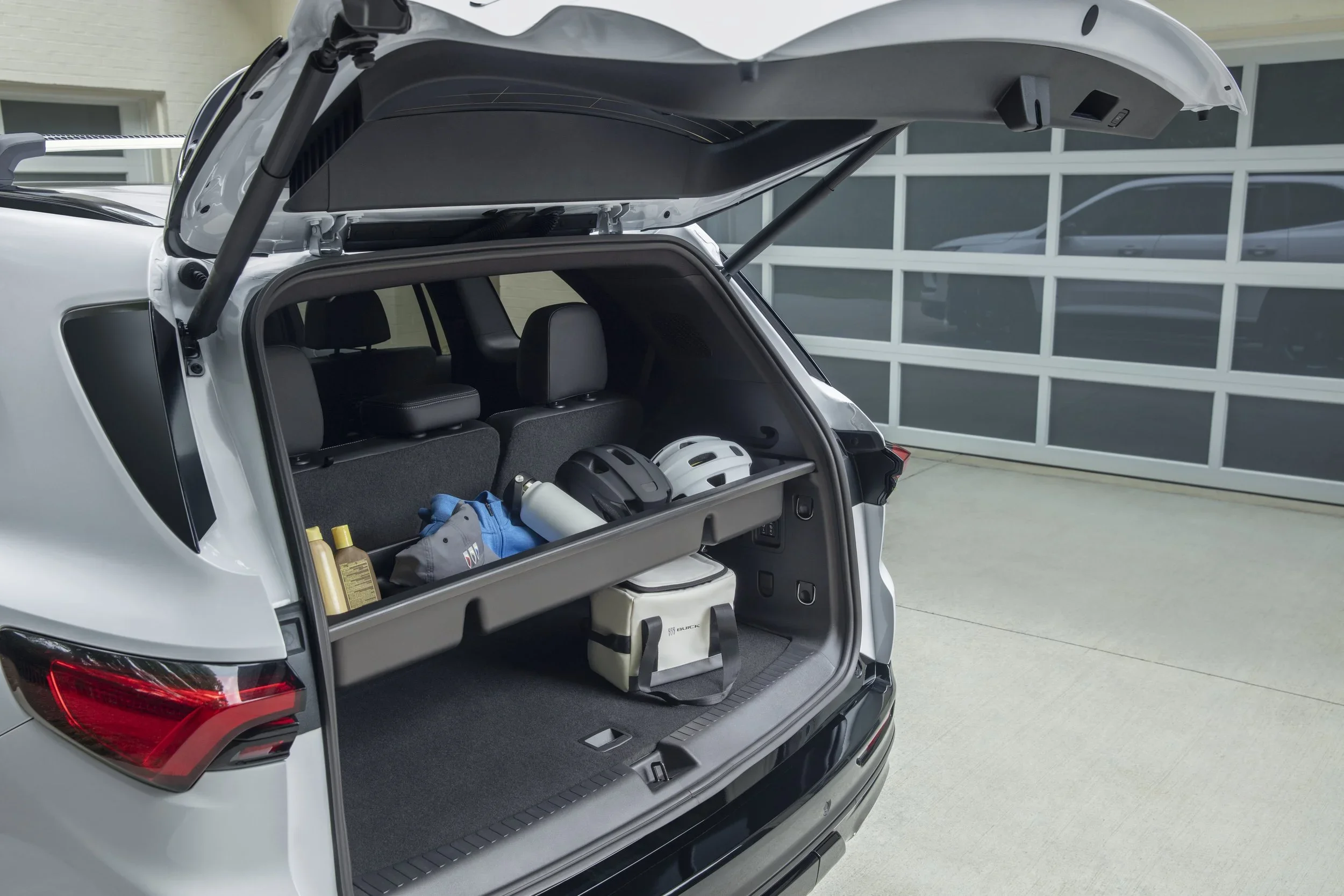 White Buick Enclave with liftgate open, cargo area holding bike helmets and cooler bag