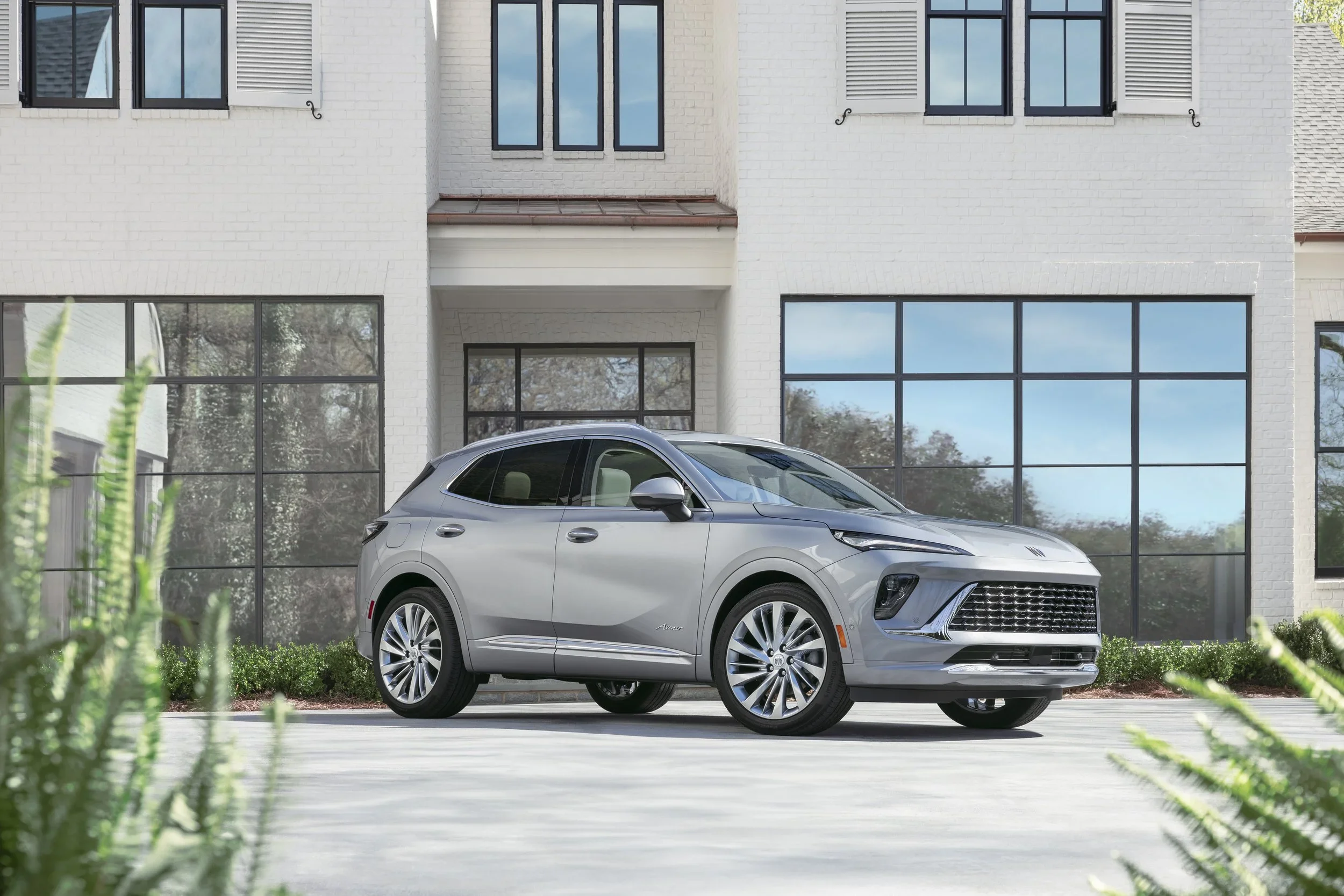 Silver Buick Envision Avenir front three-quarter exterior parked outside a white brick home
