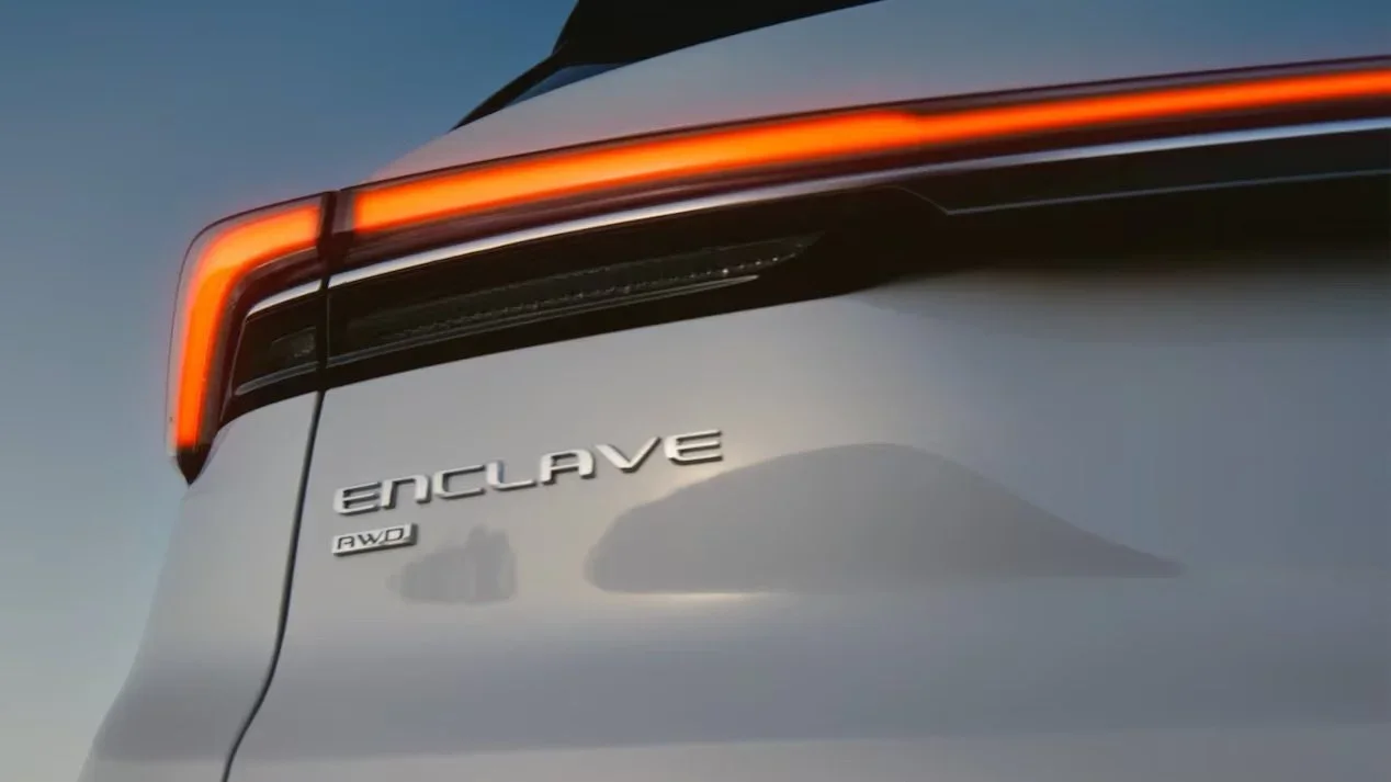 Close-up rear detail of white Buick Enclave showing lit LED taillight and AWD badging