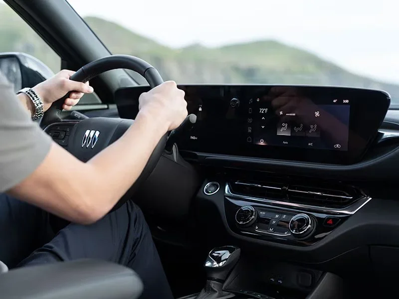Buick interior detail with driver's hands on the steering wheel and curved touchscreen display