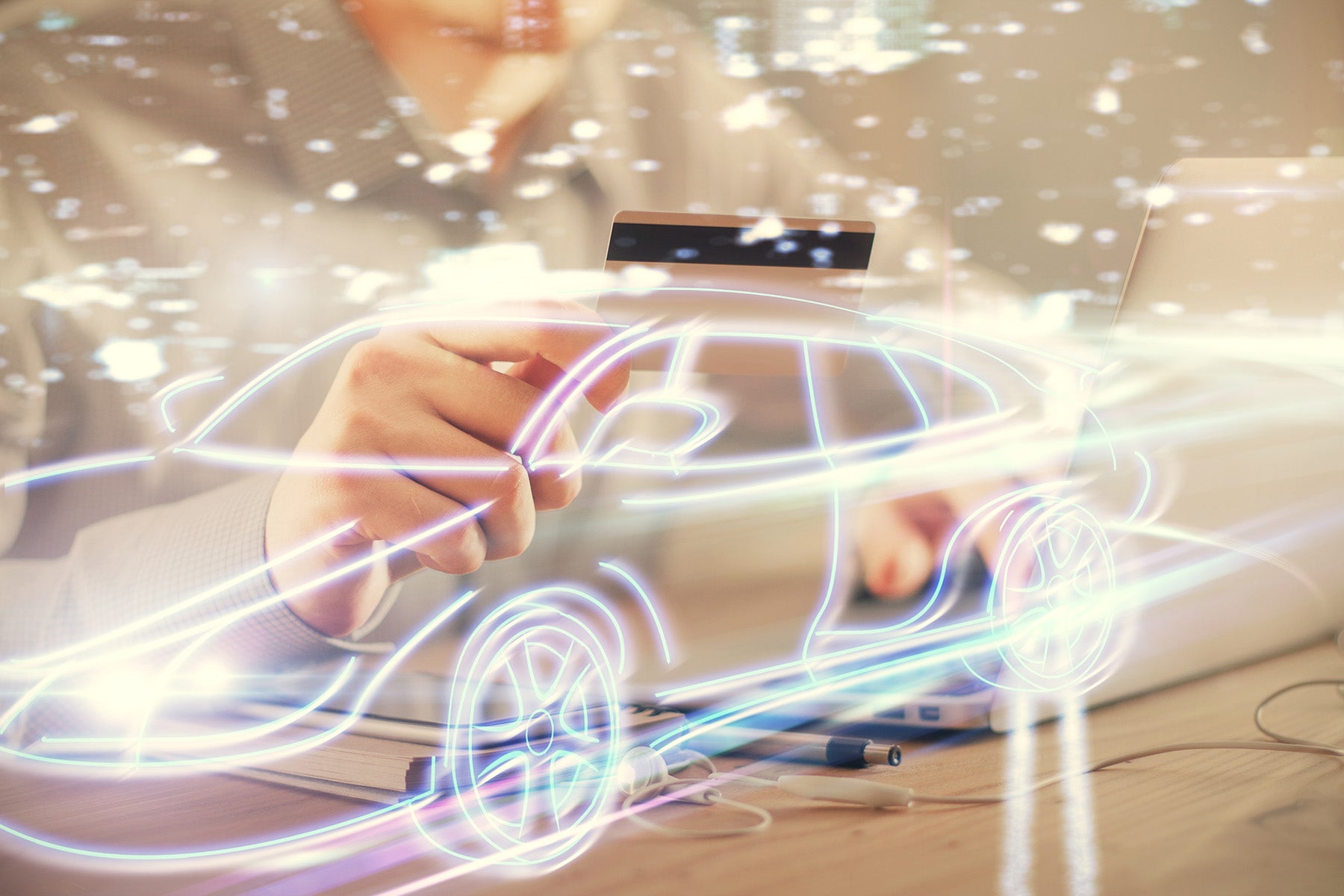 A person using a credit card while interacting with a glowing car outline on a desk.