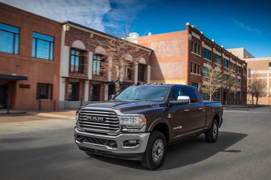 a brown 2023 ford ram driving outside of red brick buildings 