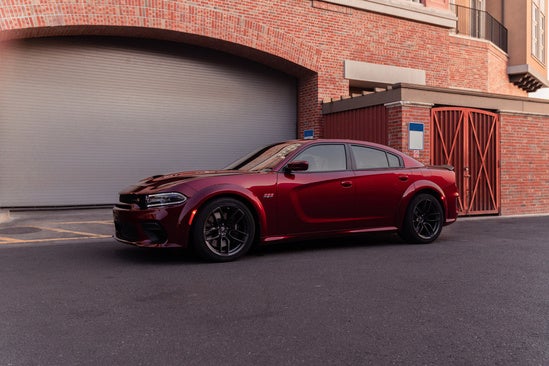 a red dodge charger parked in front of a brick building 