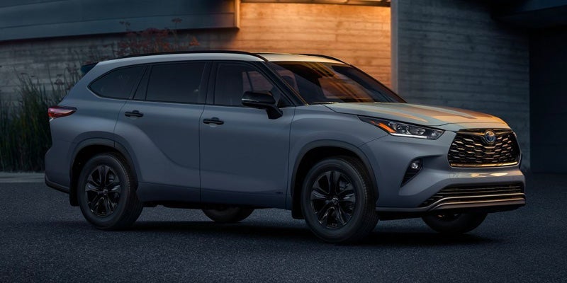 A 2024 Gray Toyota Highlander parked on a dimly lit driveway in front of a shiplap entryway. - Phil Meador Toyota, Pocatello, ID