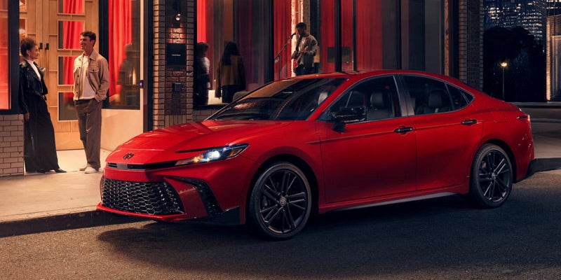 A red Toyota Camry parked in front of a restaurant